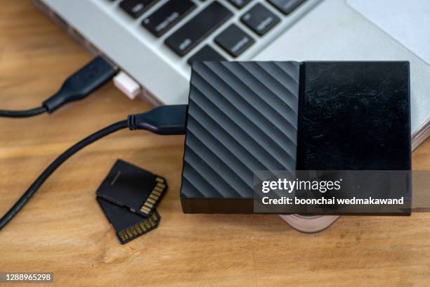 transfer or backup data between laptop and external hard disk on office desktop still life - data storage stockfoto's en -beelden