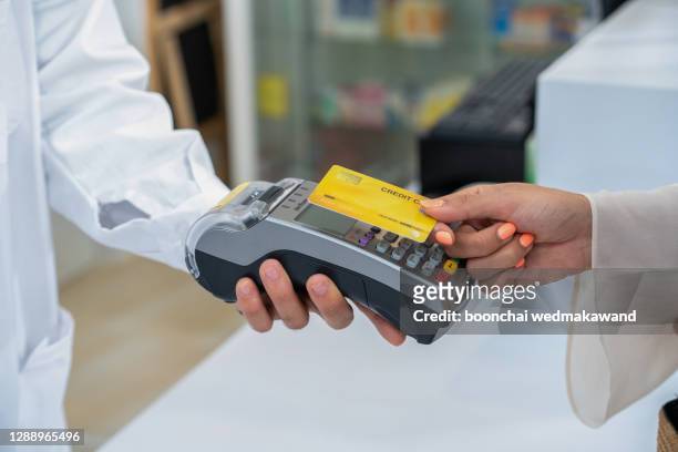client using credit card for terminal payment in pharmacy, closeup - customers pay with contactless cards imagens e fotografias de stock