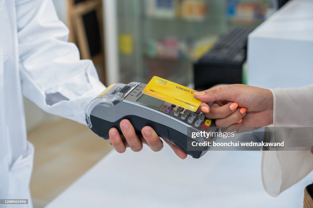 Client using credit card for terminal payment in pharmacy, closeup