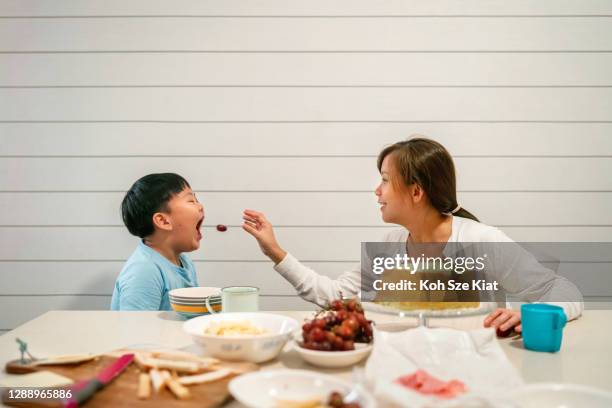 Asian mother and son playing hole in one with a grape during tea time