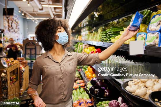 woman wearing a protective face mask shopping the in produce section of a supermarket - infected mushroom stock pictures, royalty-free photos & images