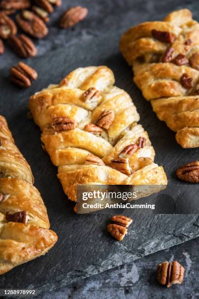 three pecan danish pastries on a textured black slate plate - danish pastries stock pictures, royalty-free photos & images