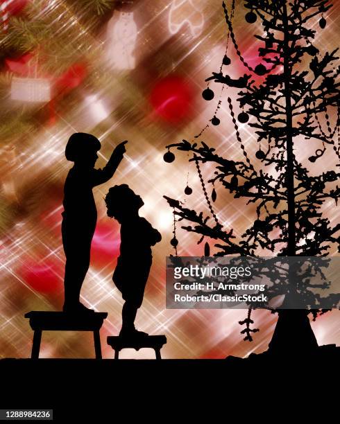 1920s 1930s Two Anonymous Silhouetted Children Standing On Stools Looking Pointing At Skimpy Christmas Tree Colorful Background