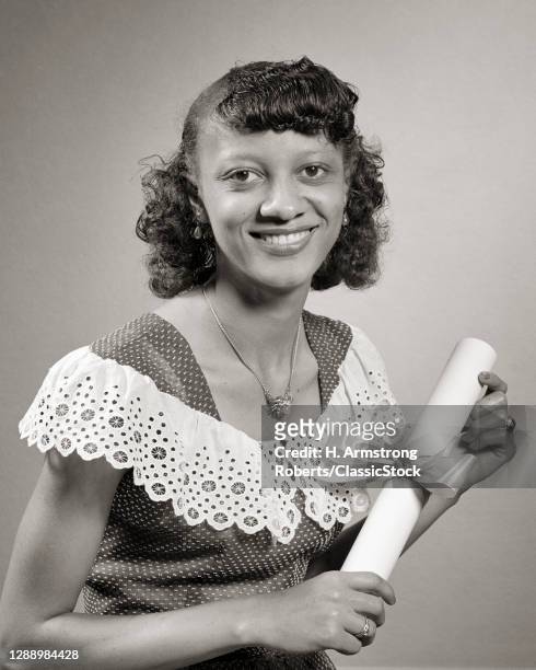 1950s African-American Woman Holding College Diploma Looking At Camera Smiling Proudly Wearing Dotted Swiss Dress Lacy Collar
