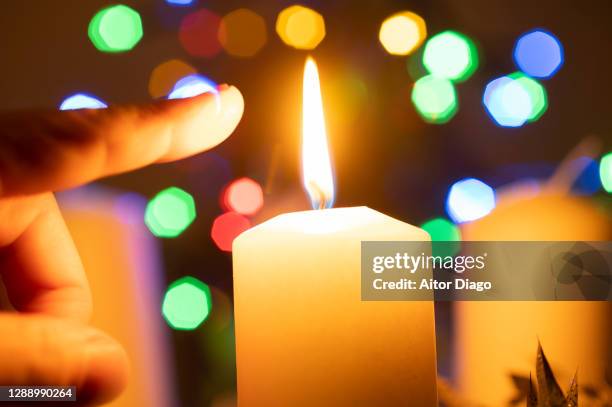 index finger of a person almost touching the flame of the candle. - self harm stock-fotos und bilder