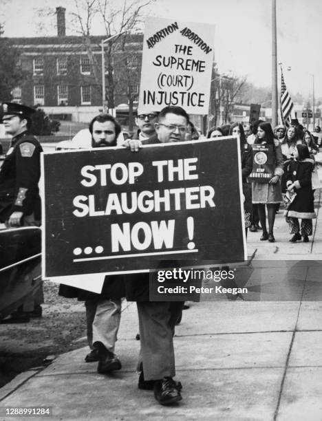 Members of a Right to Life committee holding a banner reading 'Stop the slaughter now!' and a placard reading 'The Supreme Court Injustice' during a...