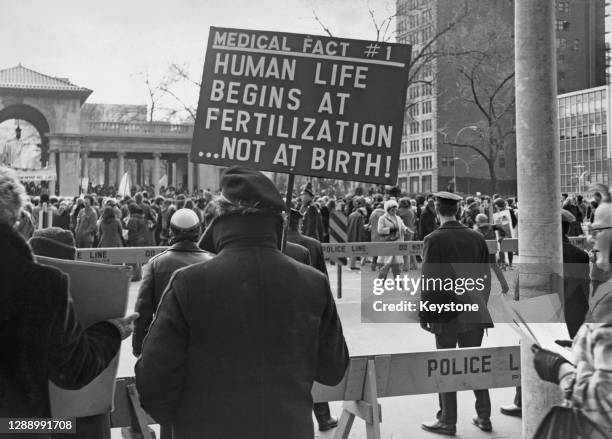 An anti-abortion protestor holding a placard reading 'Medical Fact Human life begins at fertilisation, not at birth' on a picket of the International...
