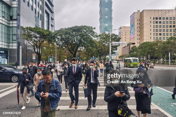 Pedestrians wearing face masks cross a street on December 02, 2020 in Taipei, Taiwan. Taiwan imposed mandatory mask-wearing regulations in some...