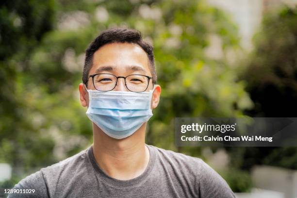 asian adult chinese man smiling behind face mask - mask man stock pictures, royalty-free photos & images