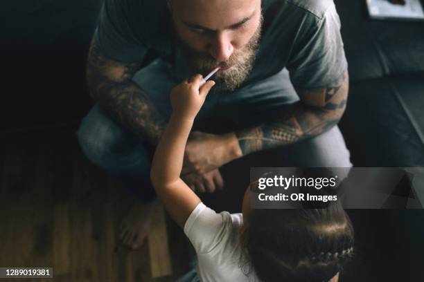 toddler girl feeding father with lollipop at home - norway food stock pictures, royalty-free photos & images