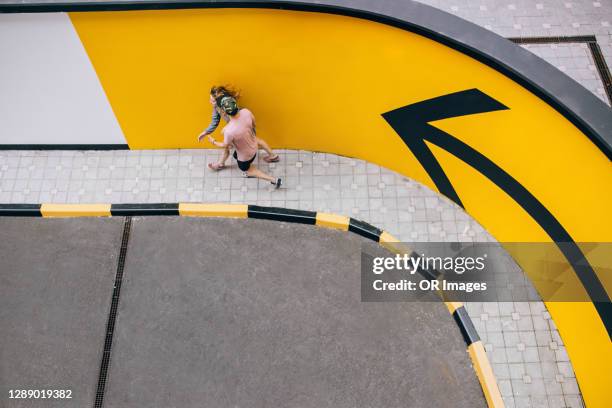 young couple walking on sidewalk at arrow sign - curve arrow stock pictures, royalty-free photos & images