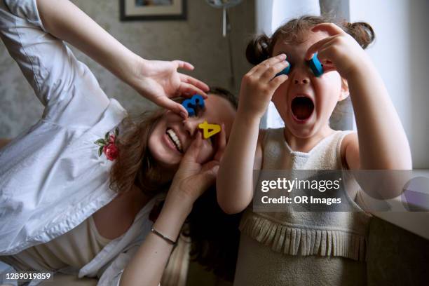 playful mother and daughter covering eyes with toy numbers - toddler laughing stock pictures, royalty-free photos & images