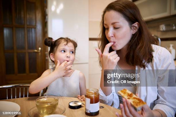 mother and daughter eating crispbread with jam at home - knäckebrot stock-fotos und bilder