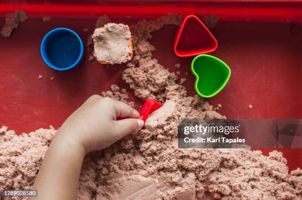 a southeast asian male toddler is playing with sand indoor - 1 kid 1 sandbox stock-fotos und bilder