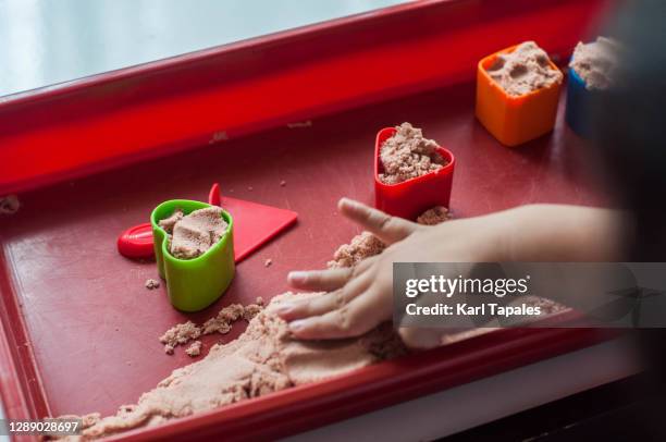 a southeast asian male toddler is playing with sand indoor - 1 kid 1 sandbox stock-fotos und bilder