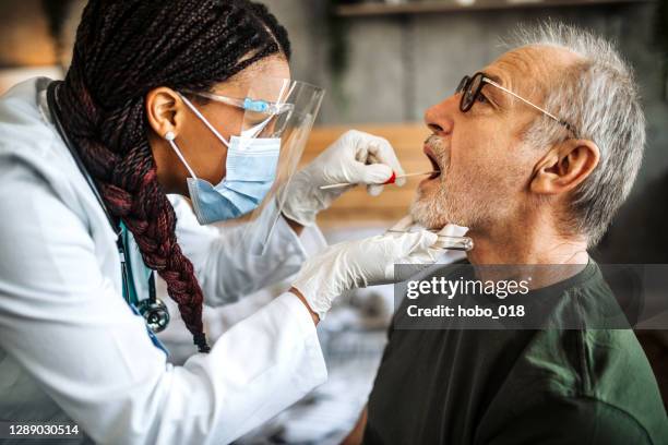 female doctor  taking sample for coronavirus testing - spit stock pictures, royalty-free photos & images