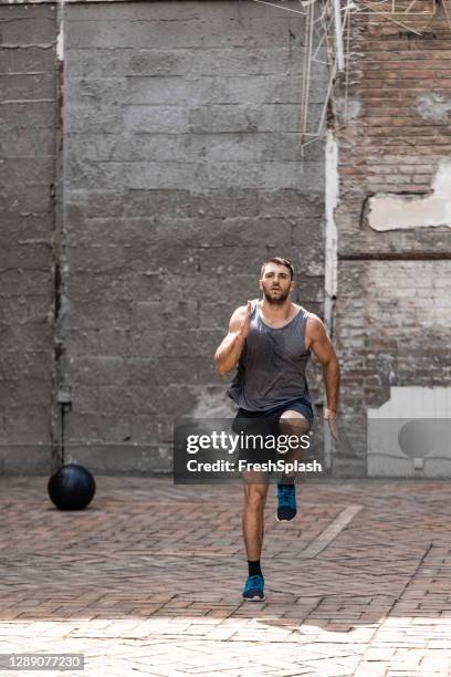 persistent young man doing high knees exercise in his backyard - high knees exercise stock pictures, royalty-free photos & images