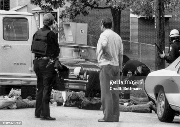 Police stand guard while other officers handcuff KKK members following a shooting between Klan members and anti-Klan demonstrators. The incident left...
