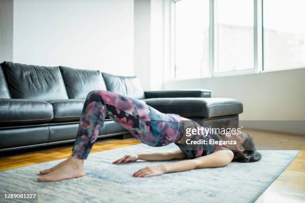 woman practicing yoga, doing glute bridge exercise, dvi pada pithasana at home - bridge stock pictures, royalty-free photos & images