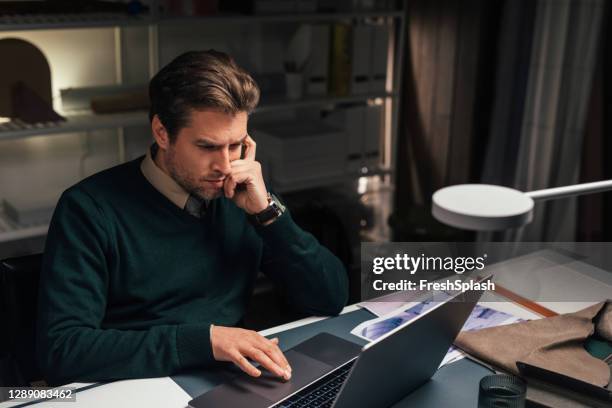 horas extras: joven ingeniero de software masculino que trabaja en una tarea de programación de su oficina tarde en la noche - hard fotografías e imágenes de stock