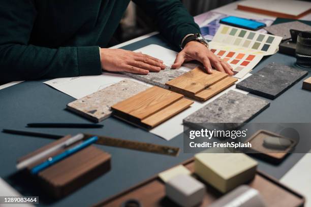 mains d’un designer d’intérieur masculin anonyme comparant des échantillons de différents matériaux dans son bureau - matière photos et images de collection