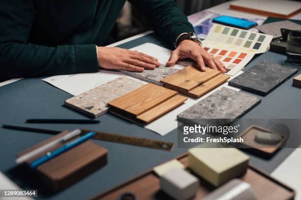 handen van een anonieme mannelijke interieurontwerper die monsters van verschillende materialen in zijn kantoor vergelijkt - architect stockfoto's en -beelden