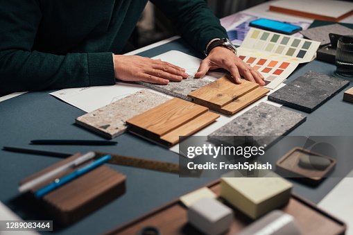 Hands of an Anonymous Male Interior Designer Comparing Samples of Different Materials in his Office Hands of an Anonymous Male Interior Designer Comparing Samples of Different Materials in his Office