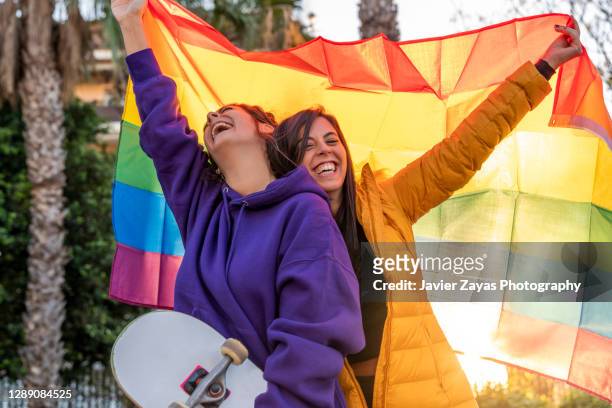 lesbian couple in the park with gay pride rainbow flag - marriage equality stock pictures, royalty-free photos & images