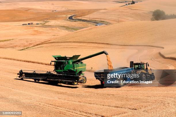 Combine unloading harvested wheat into truck in Whitman County in the Palouse hills of eastern Washington state.