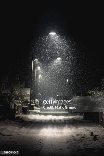 snow-covered street lit by street lights - covered car street stock pictures, royalty-free photos & images