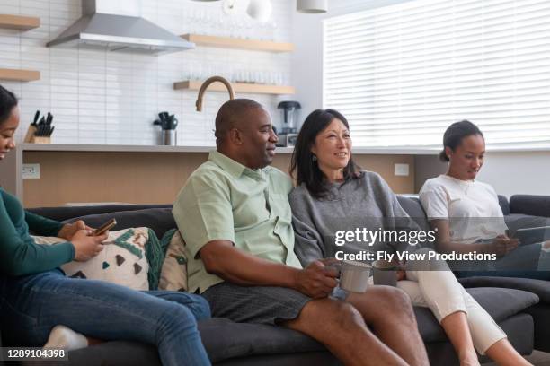 family spending afternoon together watching tv - family on couch with mugs stock pictures, royalty-free photos & images