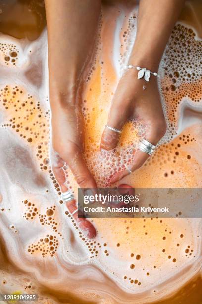 orange salt bath bomb dissolves in the hand. - bath bomb stock pictures, royalty-free photos & images