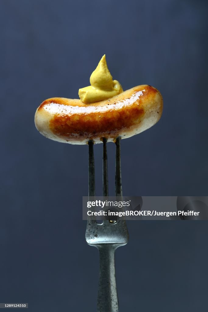 Chipolata sausages with mustard on fork, Switzerland