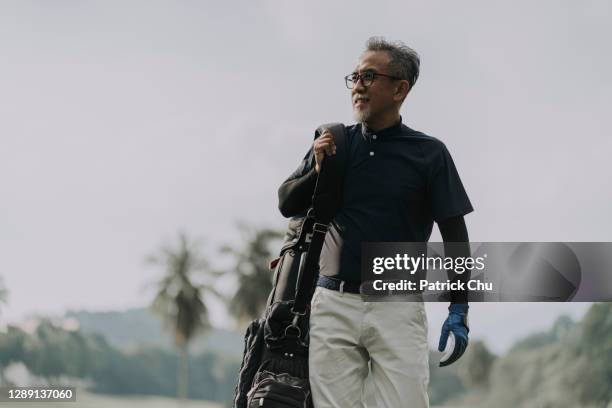 smiling and happy asian chinese mature man golfer walking at golf course - patrick walker stock pictures, royalty-free photos & images