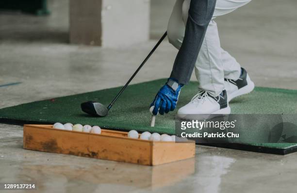 close up of golfer's hand putting golf ball on tee at driving range - country club stock pictures, royalty-free photos & images