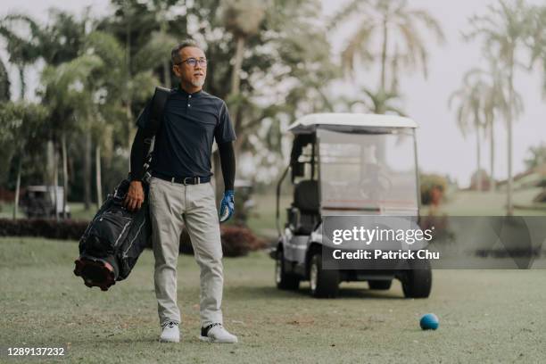 confident asian chinese mature man golfer standing at golf course - golf bag stock pictures, royalty-free photos & images