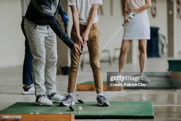 asian chinese mature man golf couch teaching young male student to play golf at driving range - practising stock pictures, royalty-free photos & images