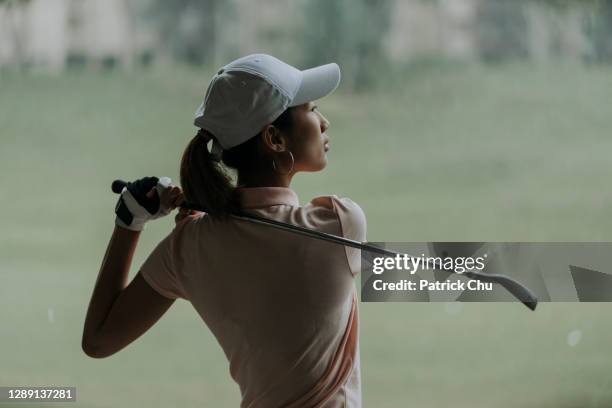 fiducioso asiatico cinese maturo donna golfista oscillante golf club al campo da golf - golf swing foto e immagini stock