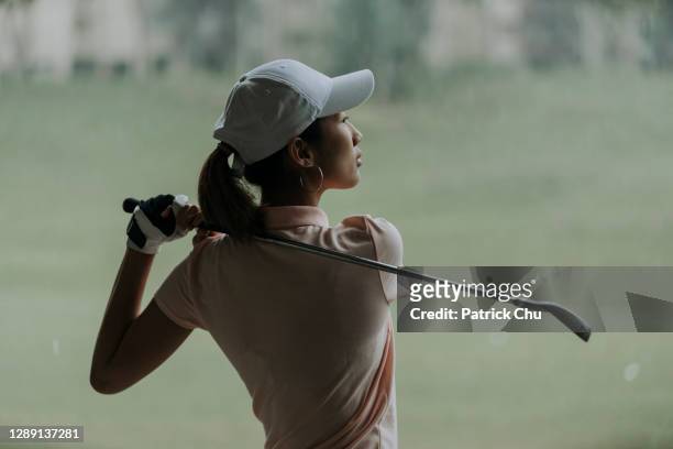 confident asian chinese mature woman golfer swinging golf club at golf course - golfer stock pictures, royalty-free photos & images