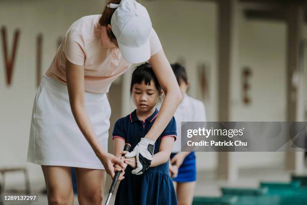 asian chinese mother golfer teaching daughter playing golf at driving range golf course - young golfer stock pictures, royalty-free photos & images