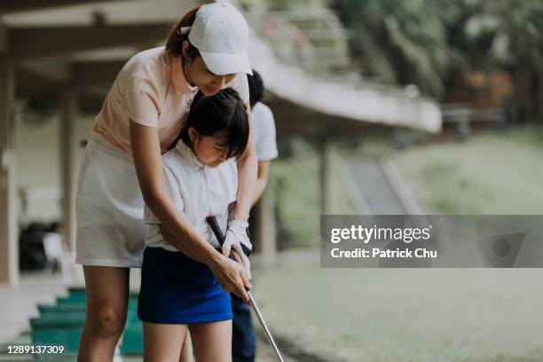 asian chinese mature woman golfer teaching young female student playing golf at driving range golf course - kids clubhouse stock pictures, royalty-free photos & images