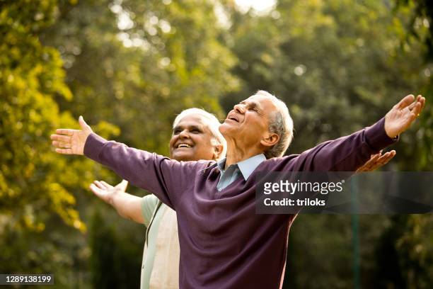 two senior men with arms outstretched at park - tranquility people stock pictures, royalty-free photos & images