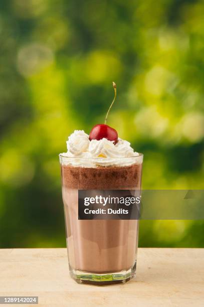 a glass of chocolate milkshake with whipped cream and cherry - chocolate shake stock pictures, royalty-free photos & images