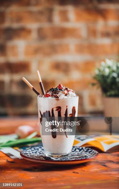 ein glas vanille-milchshake mit schlagsahne und pralinen - schokobanane stock-fotos und bilder