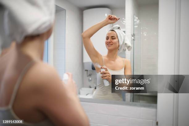 reflexion der lächelnden frau mit handtuch auf nassen haaren, sprühen deodorant unter dem arm - spraydose stock-fotos und bilder