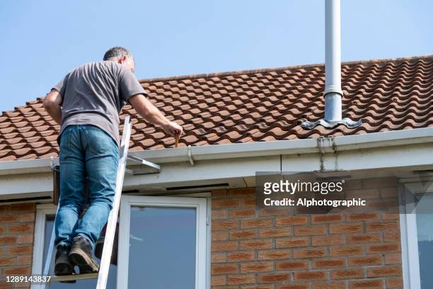 senior man cleaning gutters - leaky roof stock pictures, royalty-free photos & images