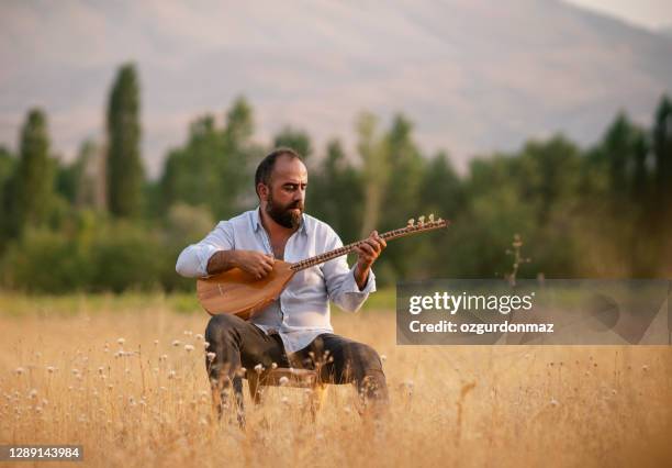 uomo turco che suona lo strumento musicale turco baglama (saz) - folk foto e immagini stock