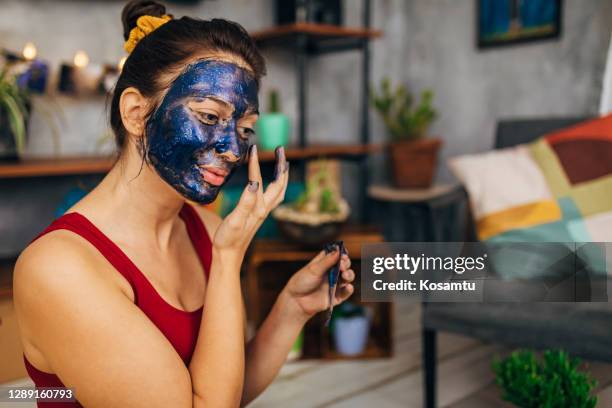 frau appkaying eine schälmaske gesichtsmaske während ihrer hautroutine - peel off mask stock-fotos und bilder