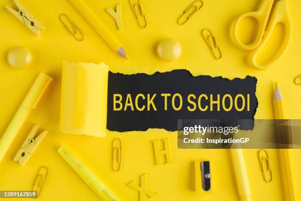 Back-to-school season concept. Top above overhead view close-up photo of yellow stationey and torn bright yellow paper over black background with copyspace
