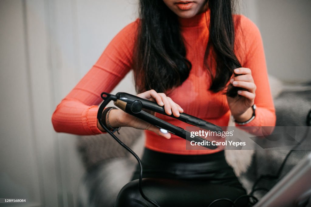 Woman using hair straightener at home